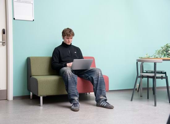 Pige med computer der sidder på en gren